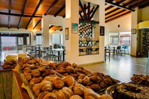 A breakfast buffet with pastries and a seating area with tables and chairs. - Villaggio Torre Ruffa Robinson (Ricadi)