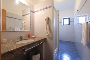 Un baño con lavamanos de mármol, ducha de mano y suelo de baldosas azules.
