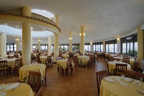 A spacious dining area with multiple tables and chairs, large windows, and a high ceiling. - Villaggio Torre Ruffa Robinson (Ricadi)