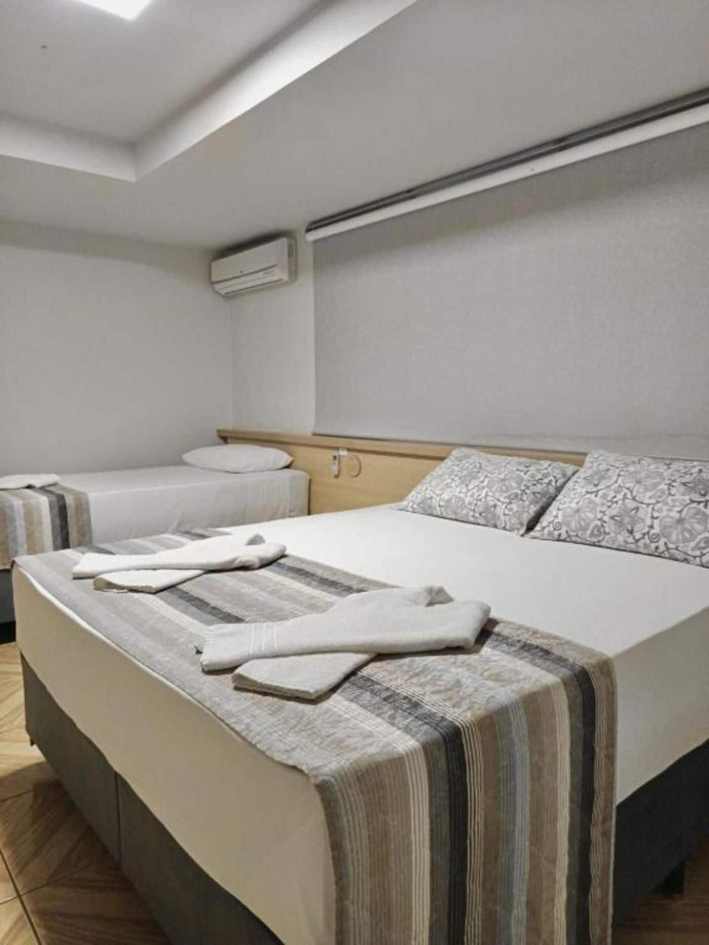 Quarto de hotel com uma cama grande, duas mesas de cabeceira, uma cabeceira e um aparelho de ar condicionado.