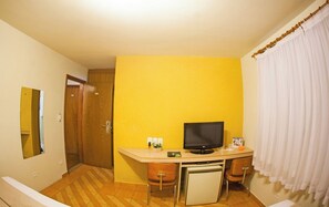 A compact room with a desk, a television, a small refrigerator, and a chair. - Harbor Self Cidade Verde (Maringá)