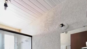 Un baño con cabina de ducha de vidrio, dos inodoros, un lavamanos y un espejo.