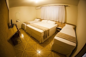 Habitación de hotel con dos camas, un escritorio, una silla y piso de baldosas.