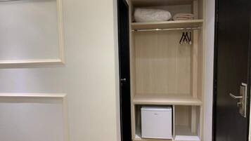 Um closet espaçoso com porta branca, um eletrodoméstico pequeno branco e roupas penduradas.