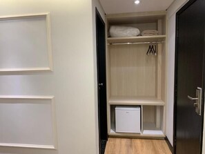 A walk-in closet with a white door, a small white appliance, and hanging clothes. - Harbor Self Cidade Verde (Maringá)