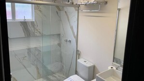 Un baño moderno con ducha envuelta en vidrio, inodoro y lavabo.