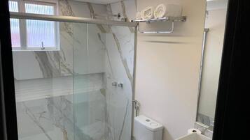 Un baño moderno con ducha envuelta en vidrio, inodoro y lavabo.