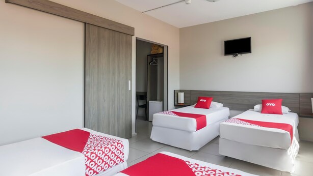 Una habitación de hotel con dos camas individuales, un televisor y una puerta corredera que da a un baño.