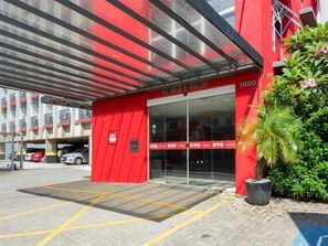 Een rood gebouw met glazen entree, een parkeerplaats en een bord waarop 'OYO HOTEL' staat.