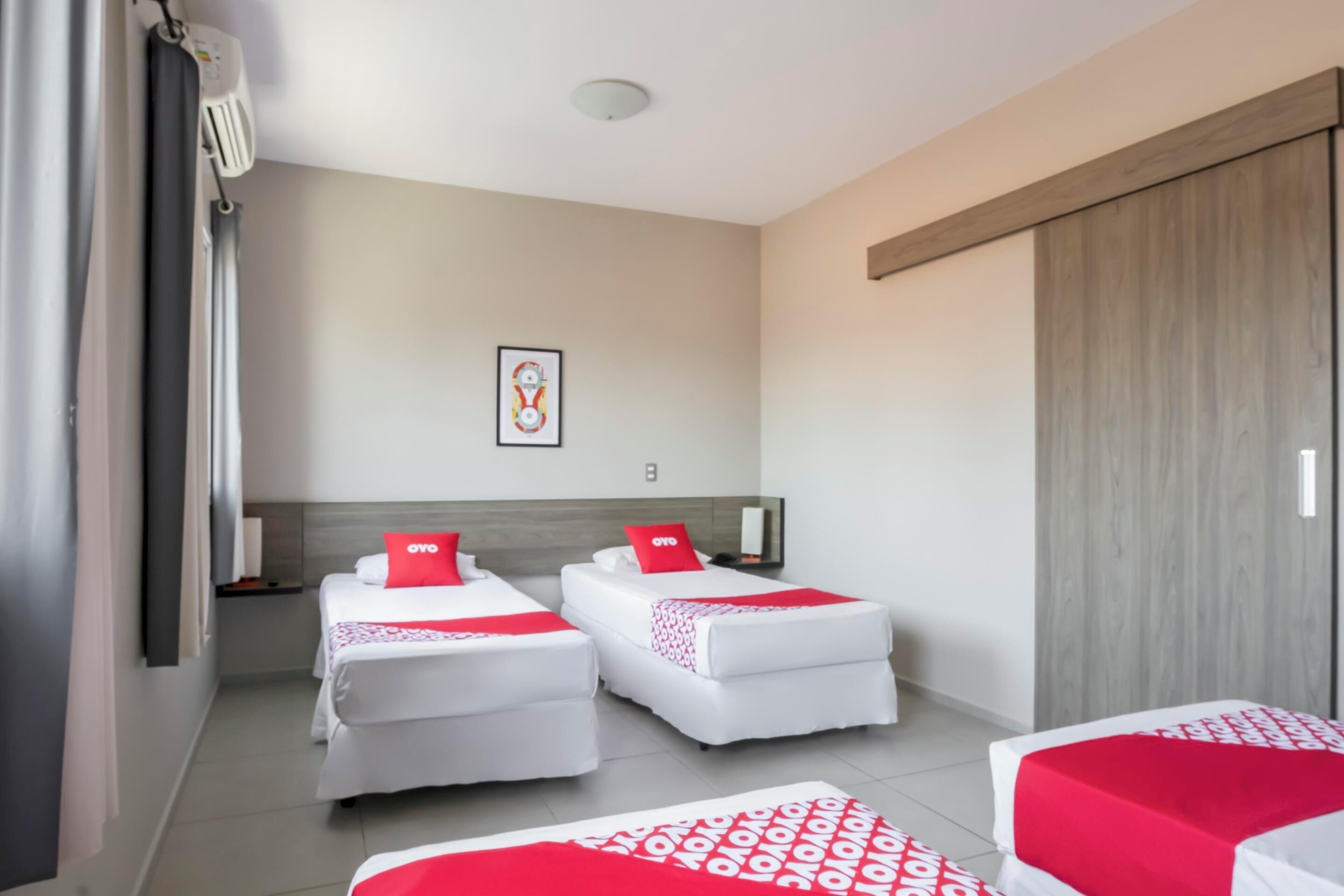 A hotel room with two beds, a large wardrobe, and a framed picture on the wall.