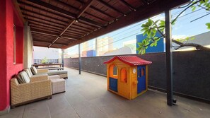 A covered outdoor area with a playhouse, seating, and a view of buildings. - I-hotel, Piracicaba (Piracicaba)