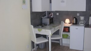 A small kitchenette with a table, chairs, a coffee maker, a toaster, and a refrigerator.