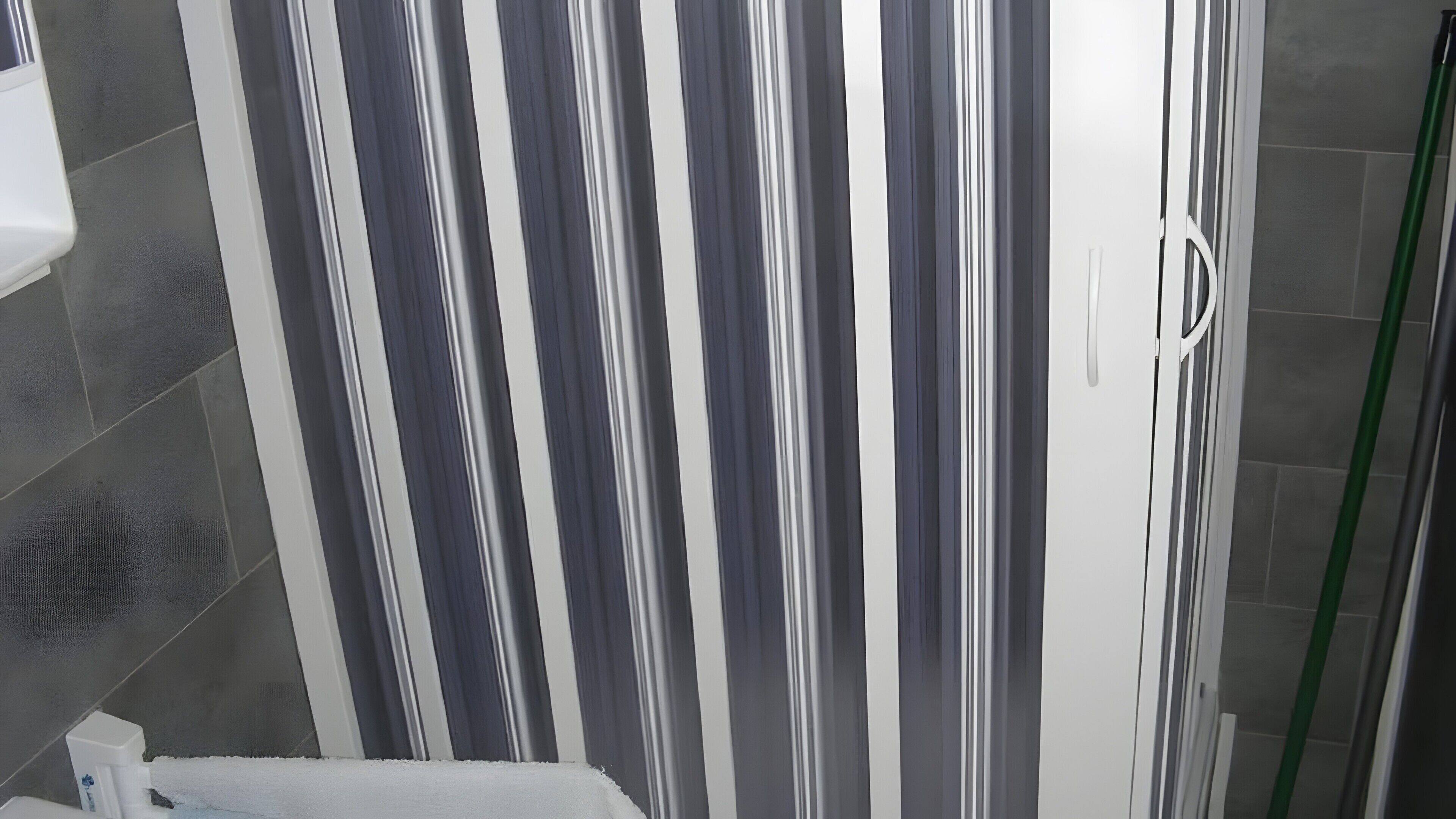 Une salle de bain avec un rideau de douche, des murs carrelés et des toilettes.
