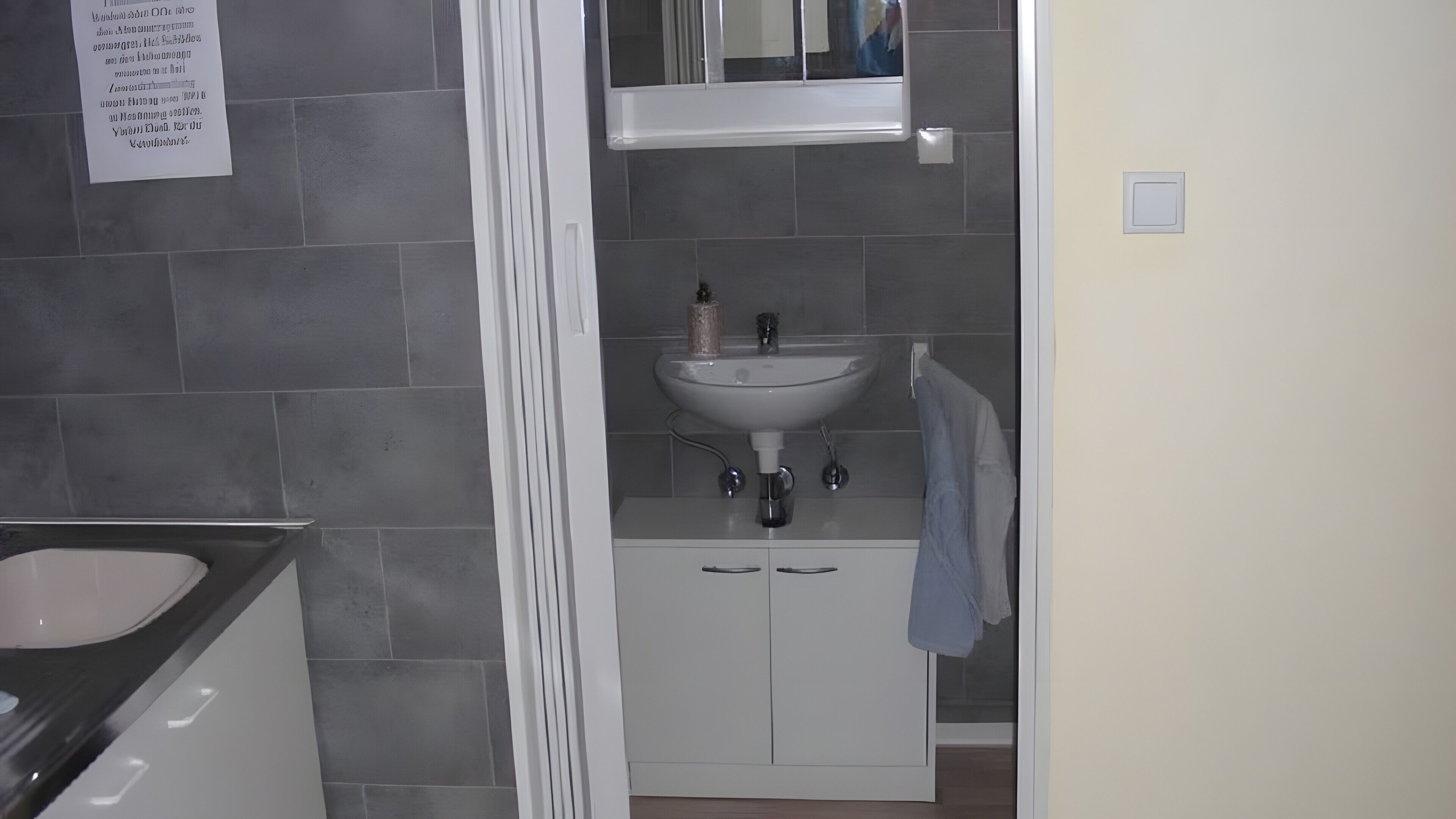 A bathroom with a white sink, mirror, and cabinets.