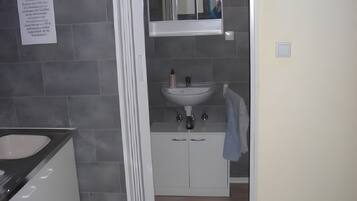 A bathroom with a white sink, mirror, and cabinets.