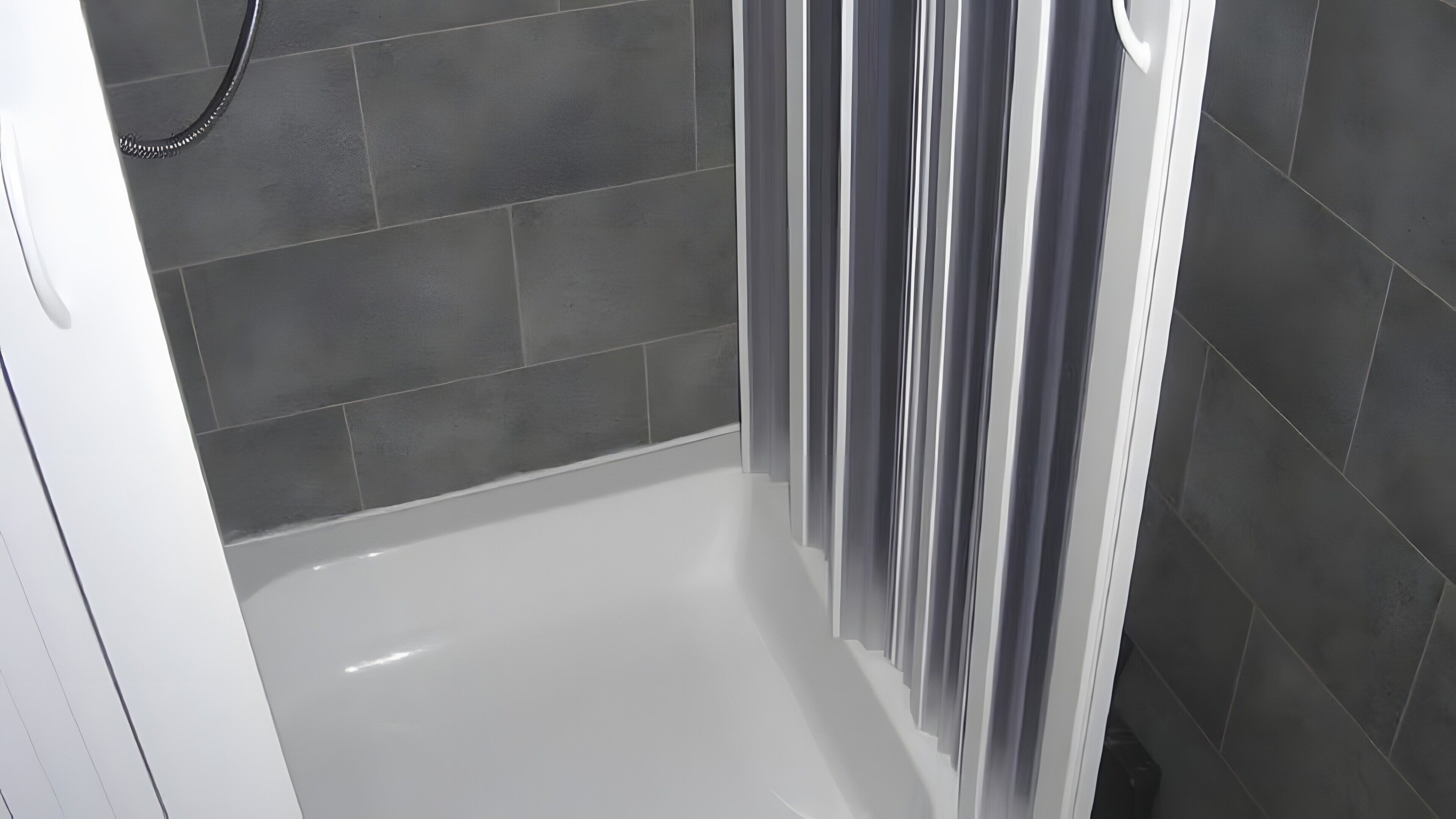 A shower area with dark tiles, a white bathtub, and a shower curtain.