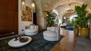 A spacious lobby with a high arched ceiling, stone walls, and modern seating areas. - MBH | Tobacco Deluxe Room (Diso Spongano)