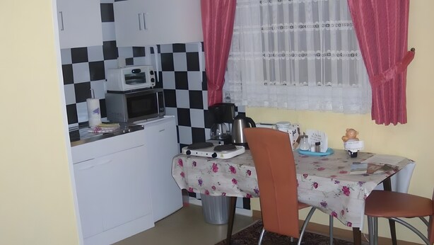 Cocina compacta con microondas, cafetera y una pequeña mesa con sillas.