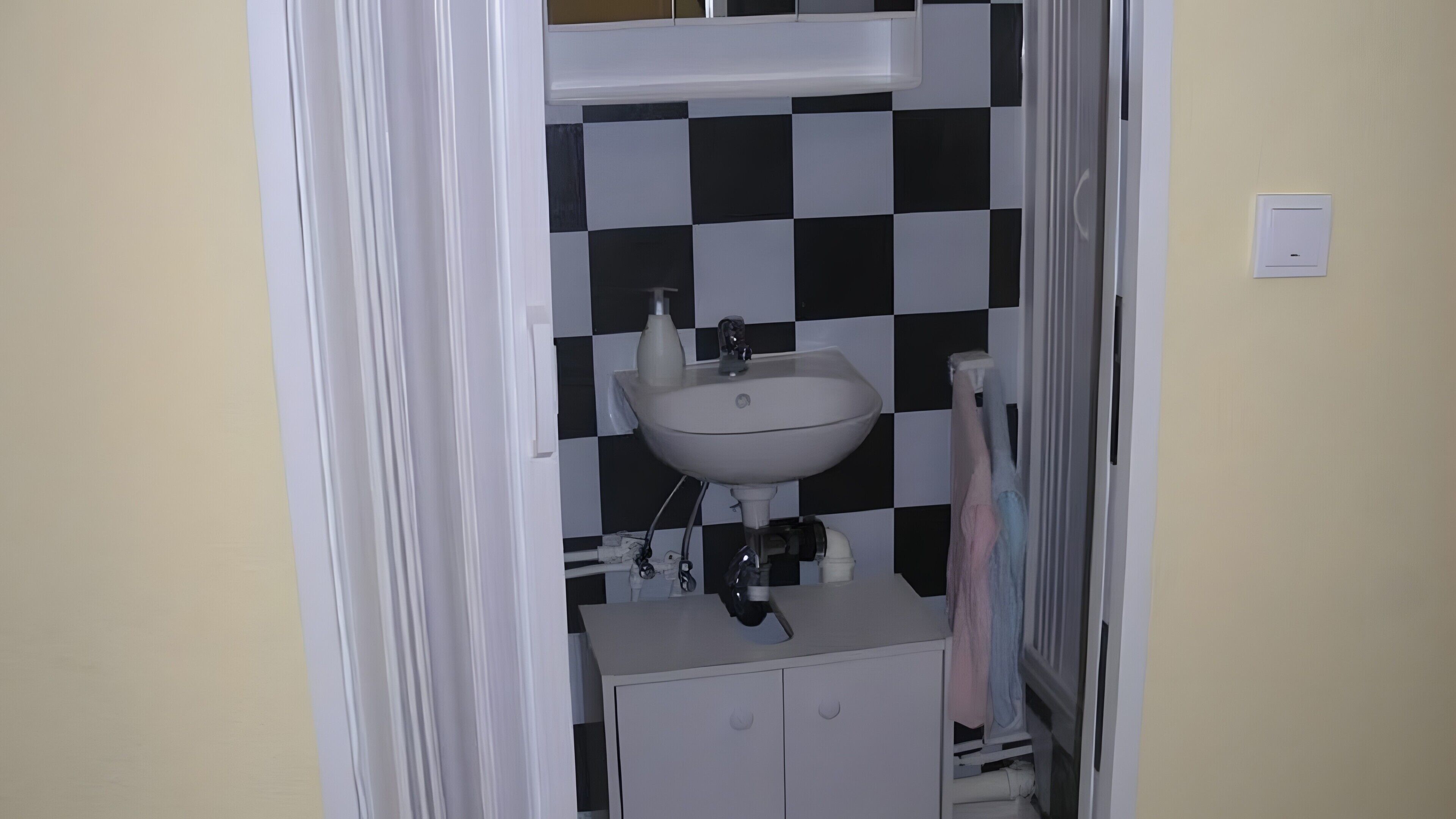 A bathroom with a white sink, black and white checkered wall, and a towel rack.