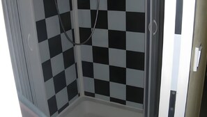 Une douche avec un mur décoré d’un motif à carreaux noirs et blancs.
