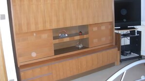 Ett träskåp med lådor och hyllor, en tv på ett stativ och en svart elektronisk apparat på en hylla.