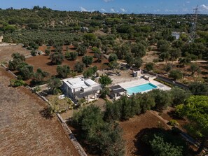 Une propriété résidentielle dotée d’une piscine, entourée d’oliveraies et située dans un paysage vallonné.