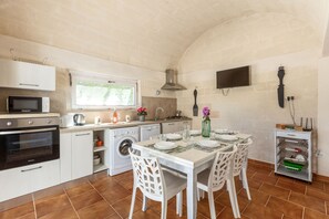 Une cuisine compacte avec un coin repas, comprenant un four à micro-ondes, un four, un lave-linge et une table à manger avec quatre couverts.