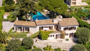 Eine großzügige Villa mit Swimmingpool, Steinwegen und üppiger Bepflanzung.
