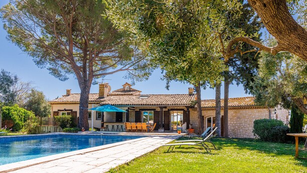 Ein Haus mit Swimmingpool, Sitzgelegenheit im Freien und einem Garten.