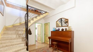 A staircase with a handrail, a wooden piano, a mirror, and a patterned rug. - Les Citronniers - Bibliothèque Guest Room with Shared Terrace, Wi-Fi & Air Conditioning (Marseille)