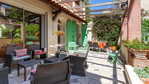 An outdoor patio with wicker furniture, a table, and chairs, surrounded by potted plants and a brick wall. - Les Citronniers - Bibliothèque Guest Room with Shared Terrace, Wi-Fi & Air Conditioning (Marseille)