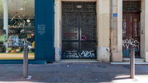 A storefront with a metal gate, a number '150' above the door, and a window displaying various items. - Les Citronniers - Bibliothèque Guest Room with Shared Terrace, Wi-Fi & Air Conditioning (Marseille)