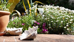 A garden with a brick pathway, a terracotta pot, and seashells. - Les Citronniers - Bibliothèque Guest Room with Shared Terrace, Wi-Fi & Air Conditioning (Marseille)