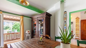 Une table à manger en bois, agrémentée d’une plante en pot, un meuble avec des portes en verre et une vue sur l’extérieur.