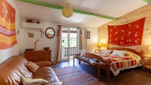 Une pièce confortable avec un lit, un canapé, un plancher en bois, un miroir, une fenêtre avec des rideaux et une tapisserie murale.