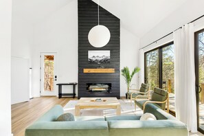 Una sala de estar moderna con chimenea, un ventanal y vistas al exterior.