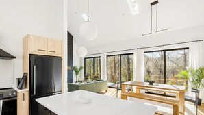A modern kitchen with a large island, built-in appliances, and a dining area with a view. - BRAND NEW Modern Luxe Scandinavian Cabin with Hot tub/Fire Pit WIFI (Blue Ridge)