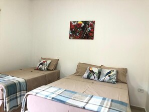 Une chambre avec deux lits, chacun étant équipé d’un oreiller et d’une couverture.