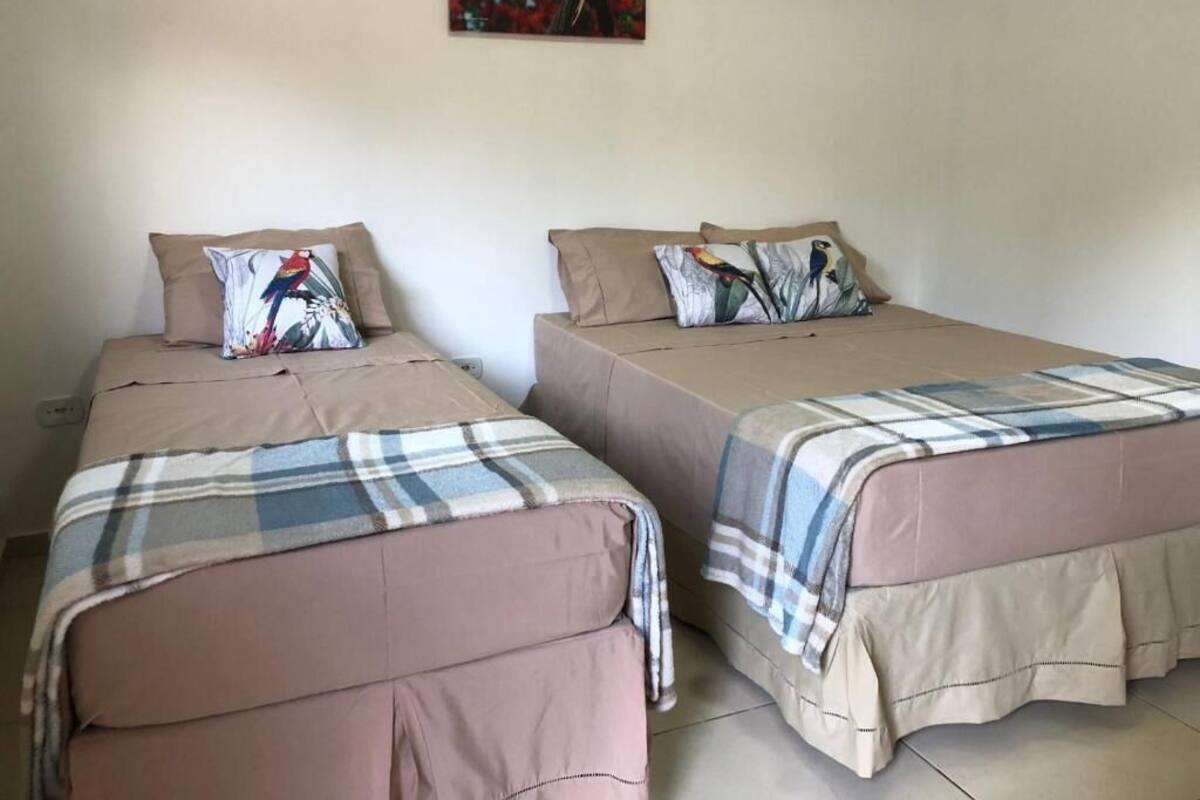 Dos camas individuales con cabeceras y pies de cama iguales, cada una con una almohada y una manta.