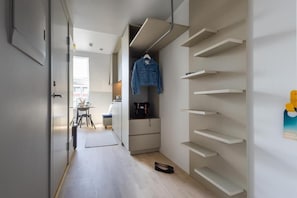 A hallway with a desk, chair, and a coat rack with a jacket. - Unity Malmö - A Studio Hotel - City Studio (Malmö)