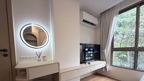 A modern bedroom with a vanity, a round mirror with lighting, a flat-screen TV, and a window with curtains. - The best vacation at Kamala Beach! Pool, gym, shuttle bus .511 (Tambon Kamala)