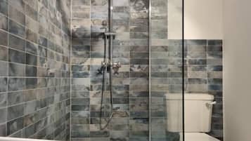 A bathroom with a shower, toilet, and patterned floor tiles.