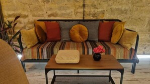Una habitación con un sofá frente a una pared con textura, una mesita de centro y una silla.