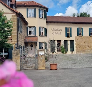 A building with a sign reading 'Stützen Mühle' and a cobblestone courtyard. - LandPension Stützenmühle  (Haßfurt)