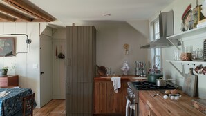 Una cucina con mobili in legno, un fornello e diversi utensili da cucina.