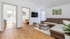 Ein modernes Wohnzimmer mit einem braunen Sofa, einem Couchtisch und einem an der Wand befestigten Flachbildfernseher.