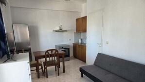 En kompakt bolig med tekøkken, spiseplads og sofa.