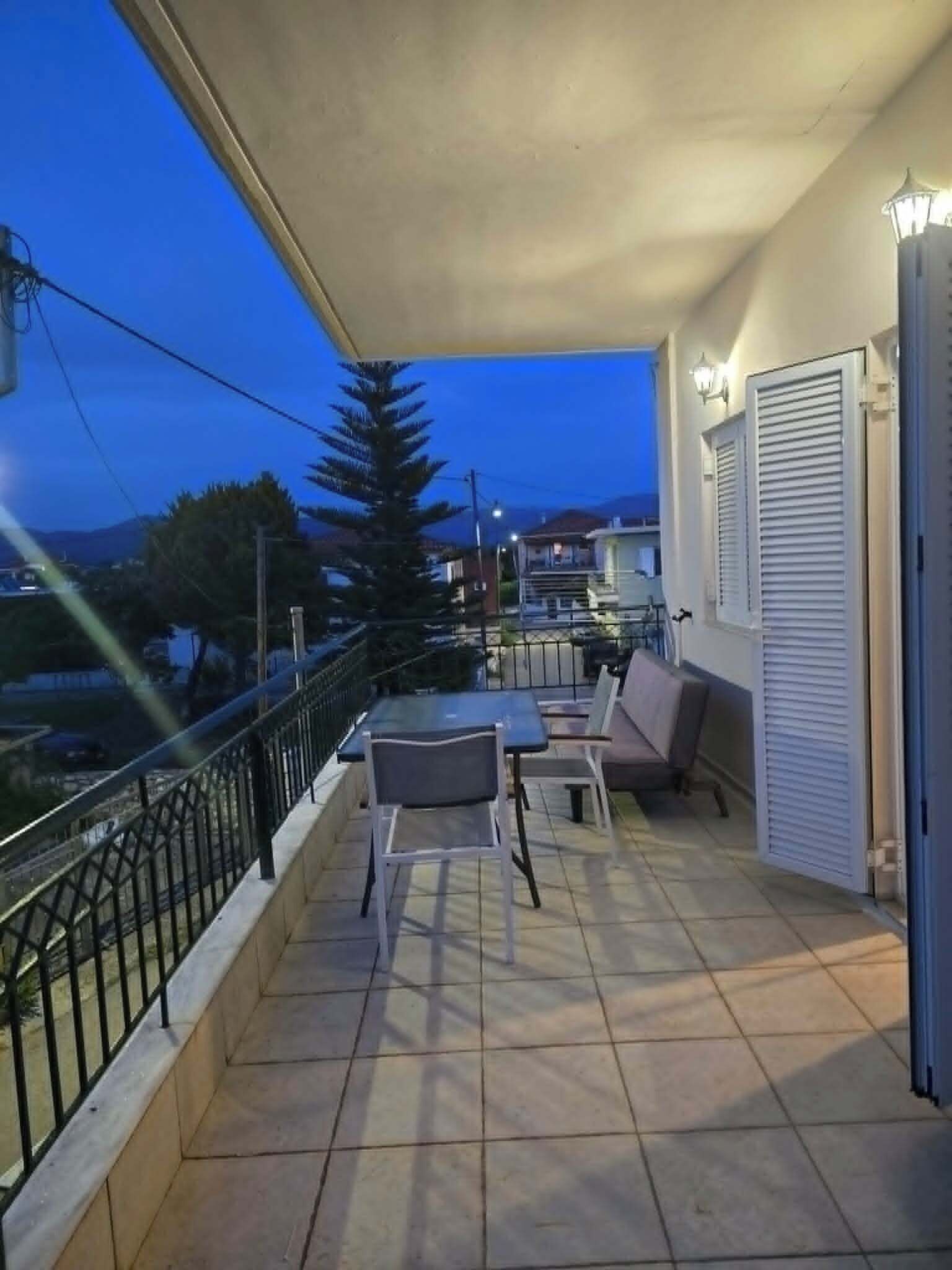 A balcony with outdoor furniture, a railing, and a view of the surrounding area.