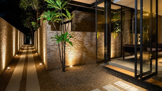 A modern building with a glass facade, a brick exterior, and a gravel pathway leading to the entrance. - Makham Villa River Kwai (Kanchanaburi)