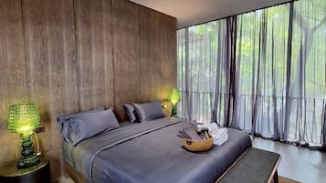 Un dormitorio moderno con una cama grande, un banco y vistas a zonas verdes.